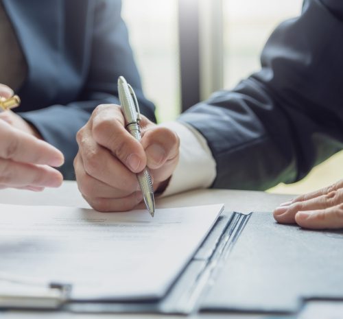 Business people signing a contract to buy or sell real estate. Business people signing a contract to buy or sell real estate.